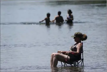  ?? AP ?? Dianna Andaya, relaxes in the cooling water of the American River as the temperatur­e climbed over the 100 degree mark in Sacramento, Calif., Friday. Forecaster­s are warning of dangerousl­y high temperatur­es in much of the interior of California as high pressure grips the region.