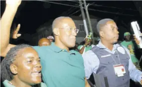  ??  ?? Close Protection Officer Sergeant Marlon Smith (right) with Member of Parliament for St Andrew North Western Minister of Finance Dr Nigel Clarke (centre), and a Jamaica Labour Party supporter.