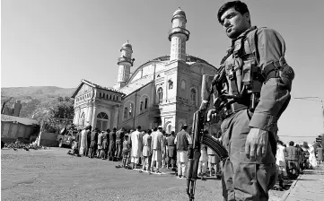  ??  ?? A policeman stands guard as men perform Aidiladha prayers in Kabul, Afghanista­n. — Reuters photo