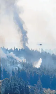  ?? Photo / Mark Mitchell ?? A helicopter using a monsoon bucket drops water on a flare-up in the Tasman bush fire in the Teapot Valley.