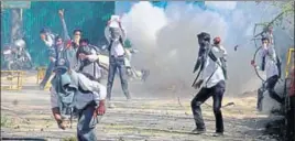  ?? PTI ?? Student hurling stones during a clash between protesters and police outside SP College in Srinagar on Monday.