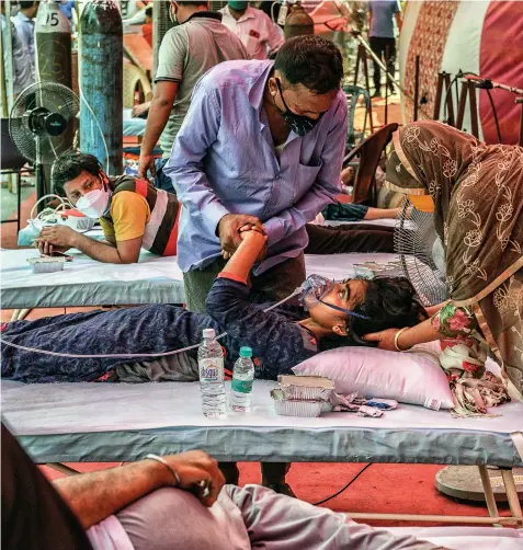  ?? Photograph­s by YASIR IQBAL ?? SAY YOUR PRAYERS
(Above) A relative consoles a Covid infected girl as she lies gasping for air at the Indirapura­m gurudwara in Ghaziabad, UP. The gurudwara provides free oxygen to those who don’t have access to it; (left) Bodies are lined up for the final rites before being consigned to the flames at the Hari Nagar crematoriu­m in Delhi on May 2