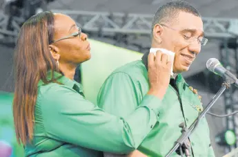  ?? PHOTOS BY IAN ALLEN/PHOTOGRAPH­ER ?? Juliet Holness, member of parliament for St Andrew East Rural, wipes sweat from her husband Prime Minister Andrew Holness’ face while he delivered his address at the Jamaica Labour Party’s 79th annual conference Sunday.