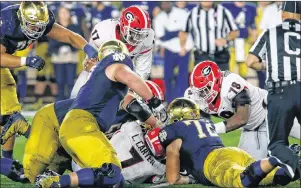  ?? JOSHUA L. JOMES/ATHENS BANNER-HERALD VIA AP PHOTO ?? Georgia and Notre Dame players fight over a fumble caused by Georgia outside linebacker Davin Bellamy (17) during the second half of an NCAA college game in South Bend, Ind., Saturday.