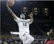  ?? CARLOS OSORIO — THE ASSOCIATED PRESS ?? Michigan guard Muhammad-Ali Abdur-Rahkman (12) makes a layup as Rutgers guard Issa Thiam (35) defends during the second half of Sunday’s game in Ann Arbor, Mich.