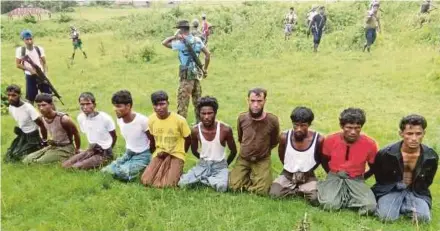 ?? REUTERS PIC ?? Rohingya men, with their hands bound, kneeling as security forces stand guard in Inn Din last year.