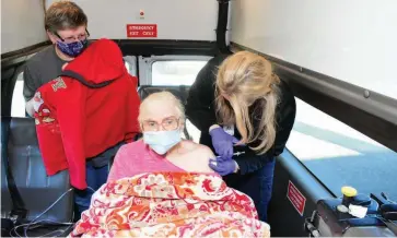  ??  ?? Bettye Baxter, 87, receives a covid-19 shot from Meghan Owens, a paramedica­l student at Southeast Arkansas College and vaccinatio­n volunteer, as Baxter’s daughter looks on inside the Baxter family’s van earlier this month near Doctor’s Orders Pharmacy in Pine Bluff. (Pine Bluff Commercial/I.C. Murrell)