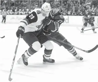  ?? JONATHAN HAYWARD, THE CANADIAN PRESS ?? Canucks defenceman Ben Hutton and Coyotes centre Dylan Strome battle for the puck during first-period action in Vancouver on Thursday.