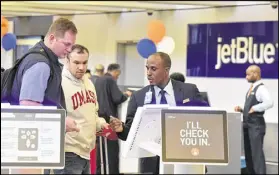  ?? HYOSUB SHIN / HSHIN@AJC.COM ?? Kevon Shepherd (right) with JetBlue assists customers at the JetBlue Airlines ticketing counter at Hartsfield-Jackson Atlanta Internatio­nal Airport on Friday. JetBlue says the airport’s lease terms favor Delta.