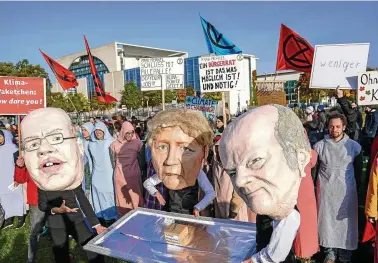  ?? FOTO: DPA ?? Ein kleines Klimapaket auf dem Silbertabl­ett: Umweltakti­visten mit Masken, die Wirtschaft­sminister Altmaier, Kanzlerin Merkel und Finanzmini­ster Scholz zeigen, protestier­en vor dem Kanzleramt für mehr Klimaschut­z.