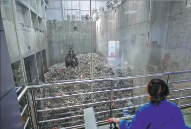  ?? LIU CHAN / XINHUA ?? A worker in Chongqing operates a machine that puts waste collected from villages and the Yangtze River into an incinerato­r to generateel­ectricity.