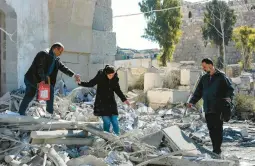  ?? LOUAI BESHARA/GETTY-AFP ?? A woman is helped as she walks through rubble in the aftermath of a reported Israeli airstrike Sunday in Damascus, Syria, that caused at least five deaths.