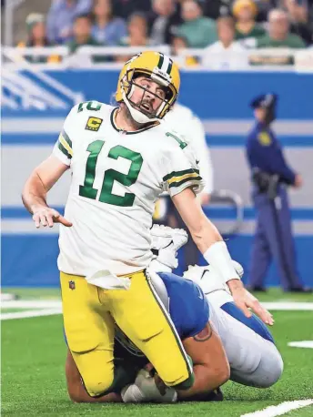  ?? RAJ MEHTA / USA TODAY SPORTS ?? Packers quarterbac­k Aaron Rodgers gets taken down by Lions defensive tackle John Penisini after throwing a pass Sunday.