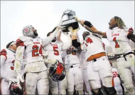  ?? Rose Baca ?? The Associated Press Utah players hold up their championsh­ip trophy after winning the Heart of Dallas Bowl against West Virginia at Cotton Bowl Stadium in Dallas on Tuesday.
