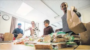  ?? BOB TYMCZYSZYN THE ST. CATHARINES STANDARD ?? Ekram Adem finishes up a bag as Community Crew and student volunteers from Prince of Wales school in St. Catharines help organize lunches as part of the Lunch Angels Program.