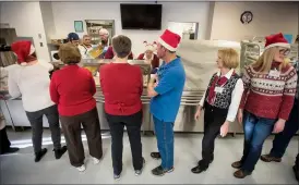  ??  ?? Volunteers line up to serve meals to their guests during the 33rd Annual Christmas Turkey Dinner at the LSCO on Christmas Monday. @TMartinHer­ald