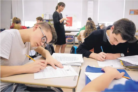  ?? STEVEN SENNE/ASSOCIATED PRESS ?? High-school students Jackson Laferriere, left, and Noah Lemoine fill out work sheets as teacher Natalie O’Brien, top center, speaks with students during a civics class called We the People, at North Smithfield High School in North Smithfield, R.I.