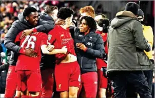  ?? PAUL ELLIS/AFP ?? Liverpool midfielder Curtis Jones (third left) is mobbed after scoring the winner in their penalty shootout with Arsenal in the League Cup at Anfield on Thursday.