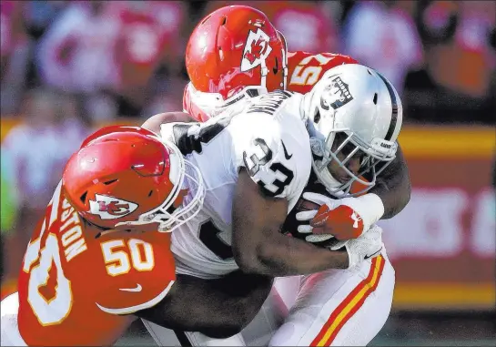  ?? Heidi Fang ?? Las Vegas Review-journal @Heidifang Raiders running back Deandre Washington is tackled by Chiefs linebacker­s Kevin Pierre-louis (57) and Justin Houston (50) in a 26-15 Kansas City victory Sunday.