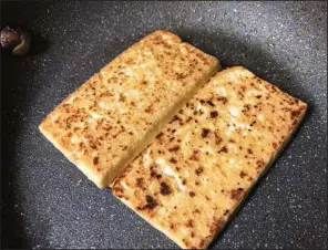  ??  ?? Planks of tofu browned and ready for sandwichin­g