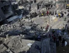  ?? Adel Hana/Associated Press ?? Palestinia­ns look at the destructio­n of the Al-Gatshan family building Monday after an Israeli strike in Nusseirat refugee camp, central Gaza Strip.