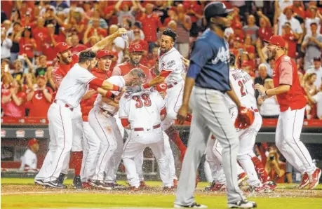  ?? THE ASSOCIATED PRESS ?? The Cincinnati Reds’ Devin Mesoraco (39) celebrates with his teammates after hitting a walk-off home run off Atlanta Braves relief pitcher Jose Ramirez during the 10th inning of Friday’s game in Cincinnati. The Reds won 3-2.