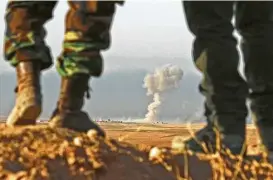  ?? Safin Hamed / AFP / Getty Images ?? Iraqi Kurdish Peshmerga fighters overlook the town of Bashiqa, some 15 miles northeast of Mosul, as smoke billows on Thursday during an operation against Islamic State jihadists to retake the main hub city.