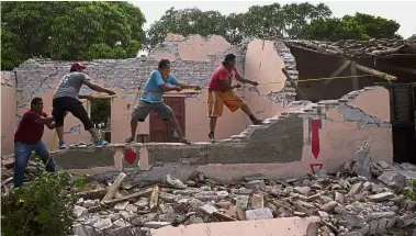  ?? — AP ?? Recovery efforts: Men pulling down the remaining section of a roof as they demolish a home destroyed by the earthquake in Asuncion Ixtaltepec, Oaxaca state, Mexico.