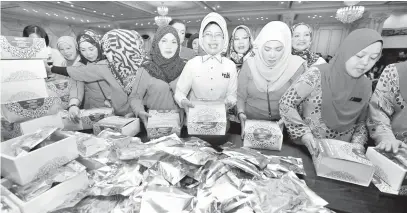  ??  ?? FATIMAH (tengah) turut serta dalam pembungkus­an kuih raya di DUN Lama pada Sabtu untuk diagihkan kepada 8,000 anggota keselamata­n dan penguatkua­saan sempena sambutan Hari Raya Aidilfitri.