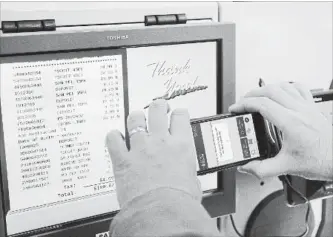  ?? STEPHAN SAVOIA THE ASSOCIATED PRESS ?? Tony D'Angelo uses the BJ's Express Scan app on his cellphone to check out after completing his shopping at the BJ's Wholesale Club in Northborou­gh, Mass.