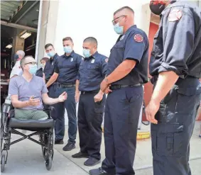  ?? RICK WOOD / MILWAUKEE JOURNAL SENTINEL ?? Dan Franecki, a utility worker, greets Milwaukee firefighters who saved his life after he was hit from behind by an impaired driver, causing severe damage to his legs and eventually leading to a double amputation. He thanked them for their heroic efforts.