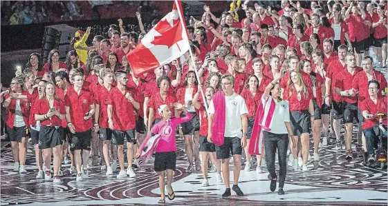  ?? RYAN REMIORZ
THE CANADIAN PRESS ?? Canada's flag-bearer, diver Meaghan Benfeito, walks into Carrara Stadium as Canadian athletes take part in the Parade of Nations Commonweal­th Games 2018 opening ceremony.