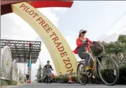  ?? REUTERS ?? Cyclists ride next to a sign of the China (Shanghai) Pilot Free Trade Zone in Shanghai.