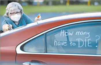  ?? BOB SELF/THE FLORIDA TIMES-UNION ?? Registered nurse Laure Hale writes on her car Tuesday before joining a motorcade to the Duval County school board building in Jacksonvil­le, Florida, where teachers and their supporters protested reopening plans amid the pandemic.