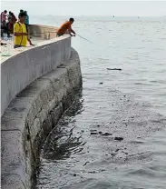  ??  ?? Slimy strip: Weekend anglers along the Esplanade trying to fish despite the strip of black oil floating on the sea.