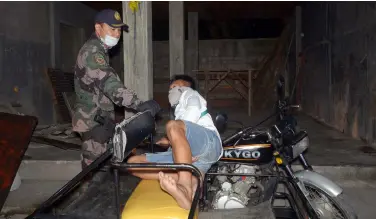  ?? BING GONZALES ?? TORIL Police Station commander Maj. Jason Baria wakes up a trisikad driver sleeping at the roadside as the curfew hours is already in force from 9 p.m. up to 5 a.m., as part of the community quarantine measures of Davao City.