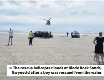  ??  ?? > The rescue helicopter lands at Black Rock Sands, Gwynedd after a boy was rescued from the water