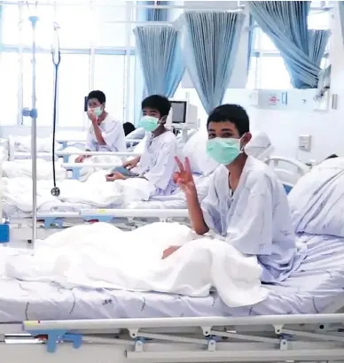  ?? THAI GOVERNMENT PUBLIC RELATIONS DEPARTMENT AND GOVERNMENT SPOKESMAN BUREAU / AFP / GETTY IMAGES ?? Members of the Wild Boars football team wave to the cameras in their hospital room in Chiang Rai, Thailand. The 12 boys rescued from a Thai cave were passed “sleeping” on stretchers through the passageway­s, a former Thai Navy SEAL said Wednesday, as...