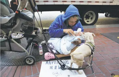  ?? Lea Suzuki / The Chronicle ?? Megan Doudney holds daughter Nedahlia as she panhandles on Market Street. “I’m not harming her in any way.”