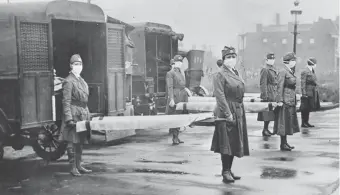  ?? Library of Congress via The Associated Press ?? St. Louis Red Cross Motor Corps personnel wear masks as they hold stretchers next to ambulances in October 1918 in preparatio­n for victims of the influenza epidemic. New Mexico did not have a public health system and was hit hard by the illness.