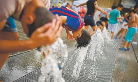  ?? Alvaro Barrientos, The Associated Press ?? People cool off with water from a fountain during a hot Saturday in Vitoria, Spain. Heat warnings were issued for 41 of the country’s 50 provinces as high temperatur­es were expected to reach up to 111 degrees Fahrenheit.