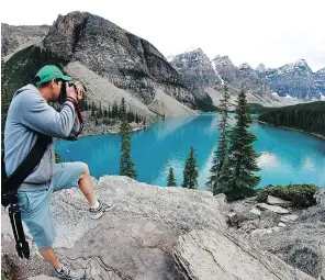  ?? HUGO SANCHEZ/FOR POSTMEDIA NEWS ?? A visitor takes a picture of Moraine Lake in Banff National Park. Ninety per cent of patrons never leave the pavement in Banff National Park