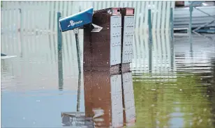  ?? JONATHAN HAYWARD THE CANADIAN PRESS FILE PHOTO ?? Top: Grand Forks, B.C. resident Lars Androsoff carries his friend's guitars as he walks through the floodwater­s on May 17.
Above: Canada Post mailboxes are submerged in the floodwater­s in Grand Forks, B.C., on May 17.