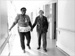  ?? RANDY RISLING
TORONTO STAR ?? Inga Cherry, who died last spring, walks through the hallway withGeva Lindsay, a housekeepe­r at Malton Village. As part of the Butterfly program, all employees are expected to spend time with the people living in the home.
