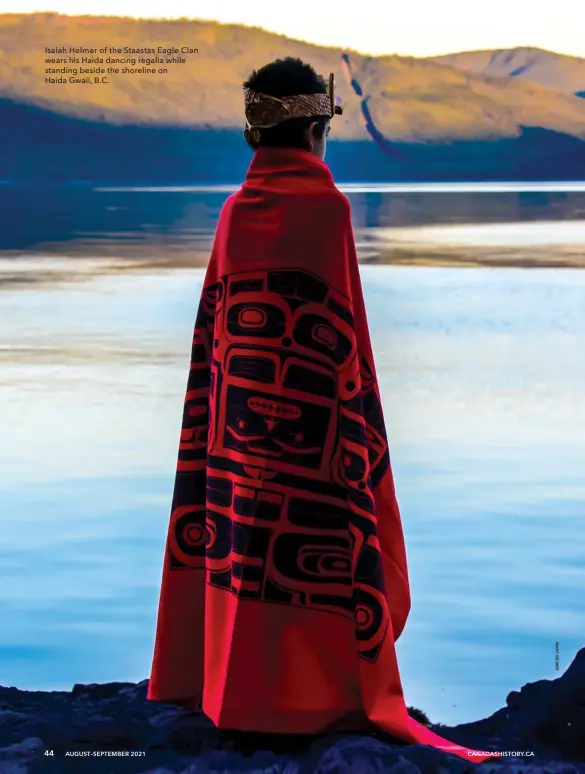  ??  ?? Isaiah Helmer of the Staastas Eagle Clan wears his Haida dancing regalia while standing beside the shoreline on Haida Gwaii, B.C.