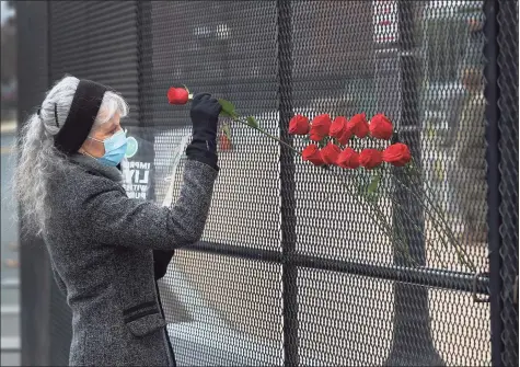  ?? Joe Raedle / Getty Images ?? Patty Raine places roses in the fence near the U.S. Capitol building on Friday, two days after a pro-Trump mob broke into the building in Washington. Raine said she was placing the roses in the fence to represent a gesture of peace among the American people.