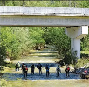  ?? NWA Democrat-Gazette/BEN GOFF ?? A search team walks through Glade Creek on Monday under U.S. 412 near Hindsville in Madison County. Multiple agencies and volunteers continue to search the area, where a 4-year-old boy and his 18-month-old sister were lost Saturday when their mother’s...