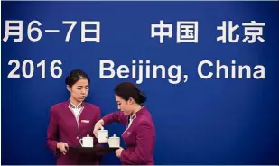  ??  ?? n e fect s nc on Two waitresses preparing to place cups of tea on a table ahead of an important meeting at a conference hall in Beijing. — AFP