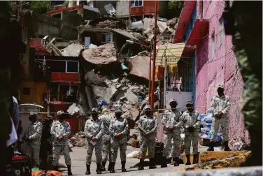  ?? Ginnette Riquelme / Associated Press ?? Security forces guard the site of a landslide in Tlalnepant­la on the outskirts of Mexico City that unleashed tons of boulders into a densely populated hillside neighborho­od. Rescuers searched for missing residents.