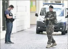  ?? Stephane de Sakutin/AFP/Getty Images ?? An armed French soldier patrols next to a forensic police officer near the site where a car slammed into soldiers in Levallois-Perret, outside Paris, on Wednesday.